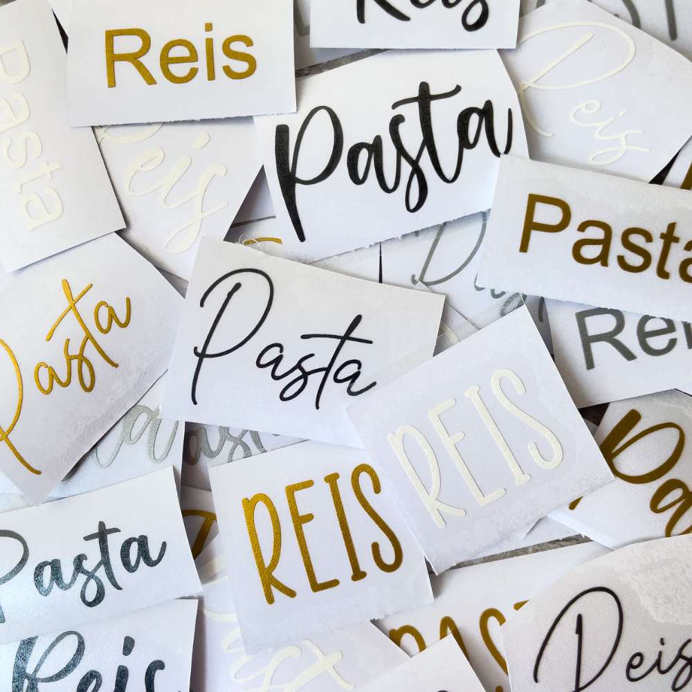 Ein verstreuter Stapel von Etiketten mit der Aufschrift Pasta und Reis in verschiedenen Schriftarten und Farben, darunter Gold, Schwarz und Weiß, auf rechteckigen Papierstücken.