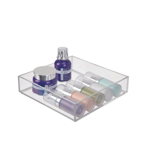 Clear container with colorful cosmetic bottles and jars on a white surface.