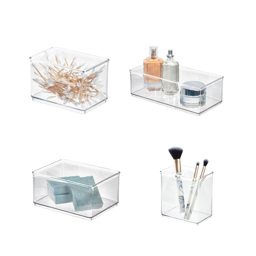 Quattro scatole di plastica trasparenti con cotton fioc, profumo, saponette e pennelli per il trucco.