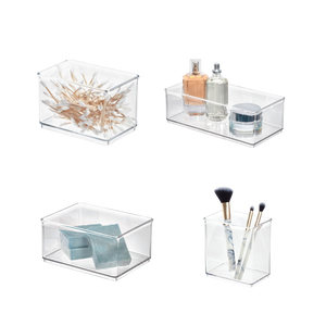 Quattro scatole di plastica trasparenti con cotton fioc, profumo, saponette e pennelli per il trucco.