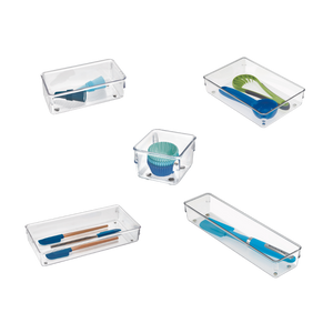 Scatole di plastica con utensili da cucina colorati e pirottini per muffin, disposti in modo uniforme su uno sfondo bianco.