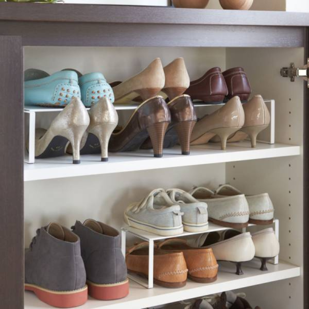 Eine ordentlich organisierte YAMAZAKI FRAME Schuhregal-Ausziehbar - Weiss mit Regalen mit Damen- und Herrenschuhen, wie High Heels, Loafer, Flats und Sneakers, die in Reihen auf und unter dem schlanken, ausziehbaren Regal angeordnet sind.