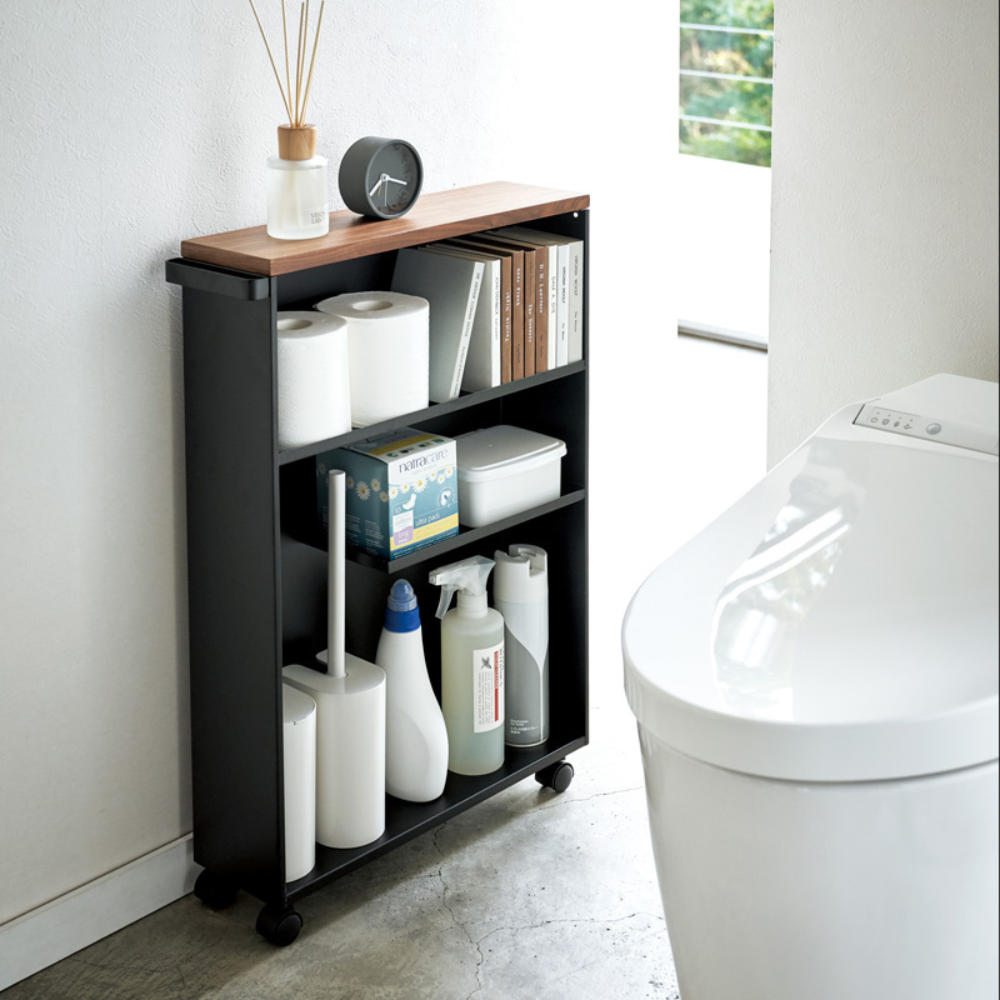 Der TOWER Aufbewahrungswagen mit Griff von YAMAZAKI in Schwarz bietet Platz für Toilettenpapier, Reinigungsmittel und mehr - ideal neben der modernen weißen Toilette im hellen Bad.