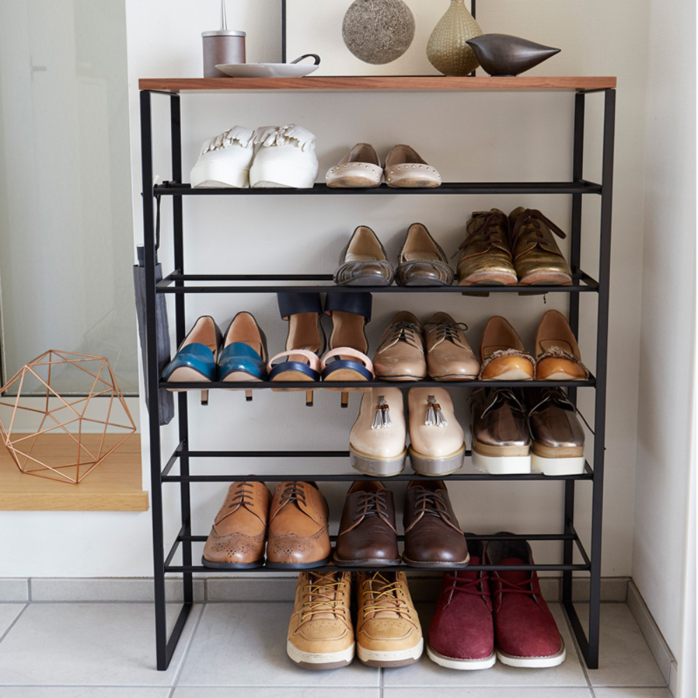 Schuhregal mit verschiedenen Schuhen, dekoriert mit Objekten obenauf.