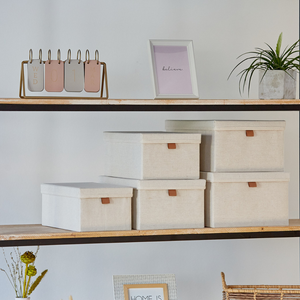 Ein Holzregal mit Love it Store it PREMIUM Aufbewahrungsboxen mit Deckel Beige (5er Set), verstärkte Kartonwände, "believe" gerahmter Print, Metallkalender auf Mittwoch, Topfpflanze und Trockenblumen-stilvolle Ordnung Zuhause.