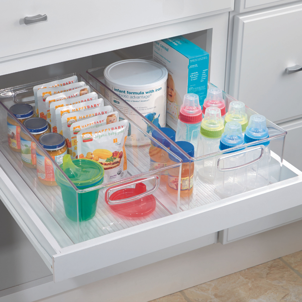 In einer aufgeräumten Küchenschublade steht das iDesign Küchen-Set MINI (5-teilig) mit klaren, stapelbaren Ordnungssystemen für Babynahrung, Snacks, Beutel und Flaschen mit farbigen Verschlüssen. Weiße Schubladen und Schränke unterstreichen den organisierten Look.