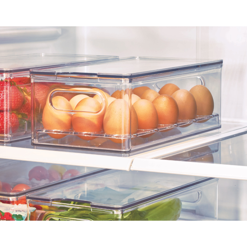 Transparente Box mit Eiern im Kühlschrank, daneben Erdbeeren und Gemüse.