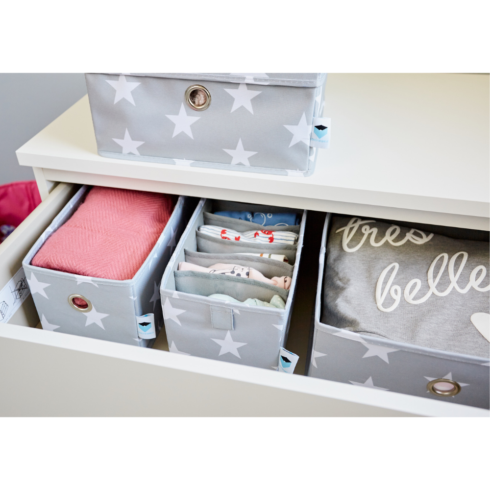 Eine Schublade mit STAR Organizer breit Grau - Set 2 Stk von Love it Store it bewahrt gefaltete Babykleidung, eine rosa Decke und ein "très belle" Hemd auf - ideal als Organizer Kinderzimmer, um alles ordentlich und getrennt zu halten.