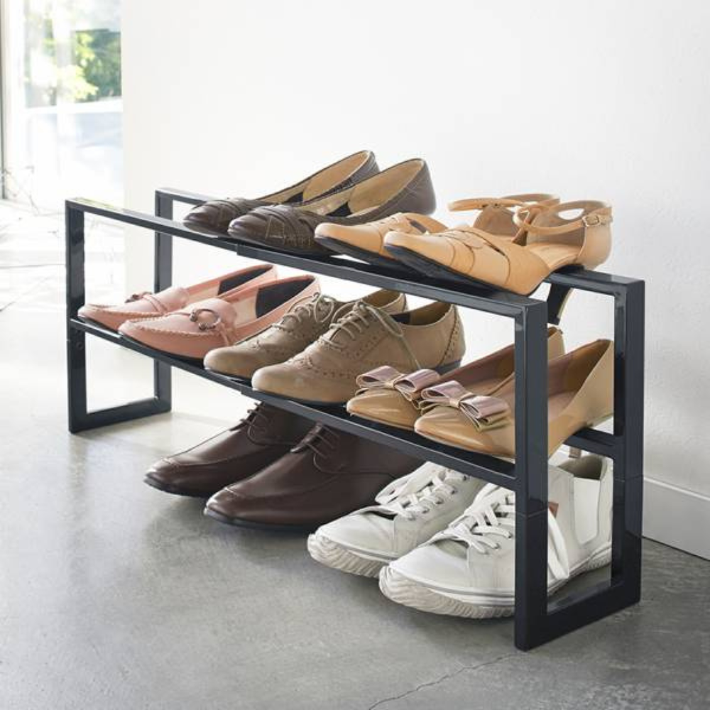 Schuhregal mit verschiedenen Schuhen, steht auf Betonboden neben einer weißen Wand.