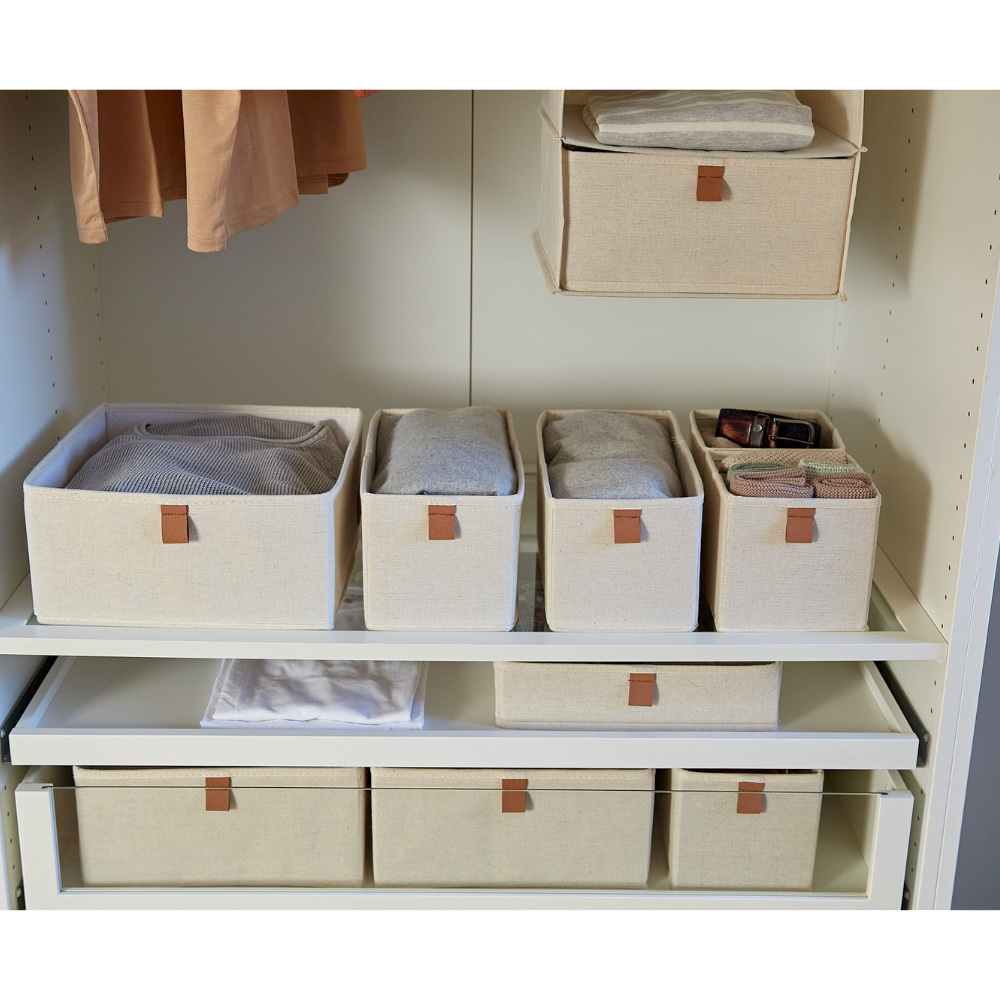 Fünf beigefarbene Stoffbehälter aus dem Love it Store it PREMIUM Organizer Beige Set sind ordentlich auf weißen Schrankregalen platziert. Einige enthalten gefaltete Kleidung und Accessoires, während hängende Kleidungsstücke und Wäsche ebenfalls sichtbar sind.
