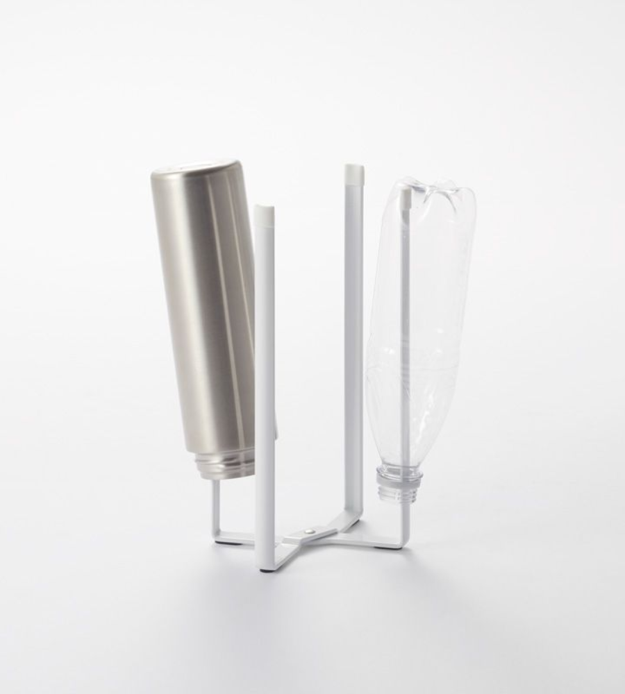 Auf dem YAMAZAKI TOWER Mehrzweckständer Küche - Weiss mit vier vertikalen Armen stehen eine Metallflasche und eine durchsichtige Plastikflasche auf dem Kopf, vor einem schlichten weißen Hintergrund.