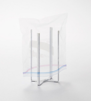 Der YAMAZAKI TOWER Mehrzweckständer Küche - Weiss hält einen durchsichtigen Plastik-Ziplock-Beutel offen. Dieser faltbare, vierzackige Küchenständer vereinfacht die Arbeit und wird vor einem schlichten weißen Hintergrund gezeigt.