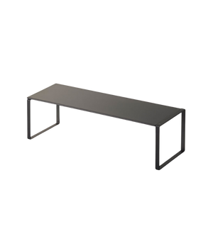Der FRAME Schuhregal ausziehbar von YAMAZAKI in Schwarz ist eine minimalistische Bank mit flachem Sitz und offenen, rechteckigen Beinen an jedem Ende - ideal zur praktischen Schuhaufbewahrung vor weißem Hintergrund.