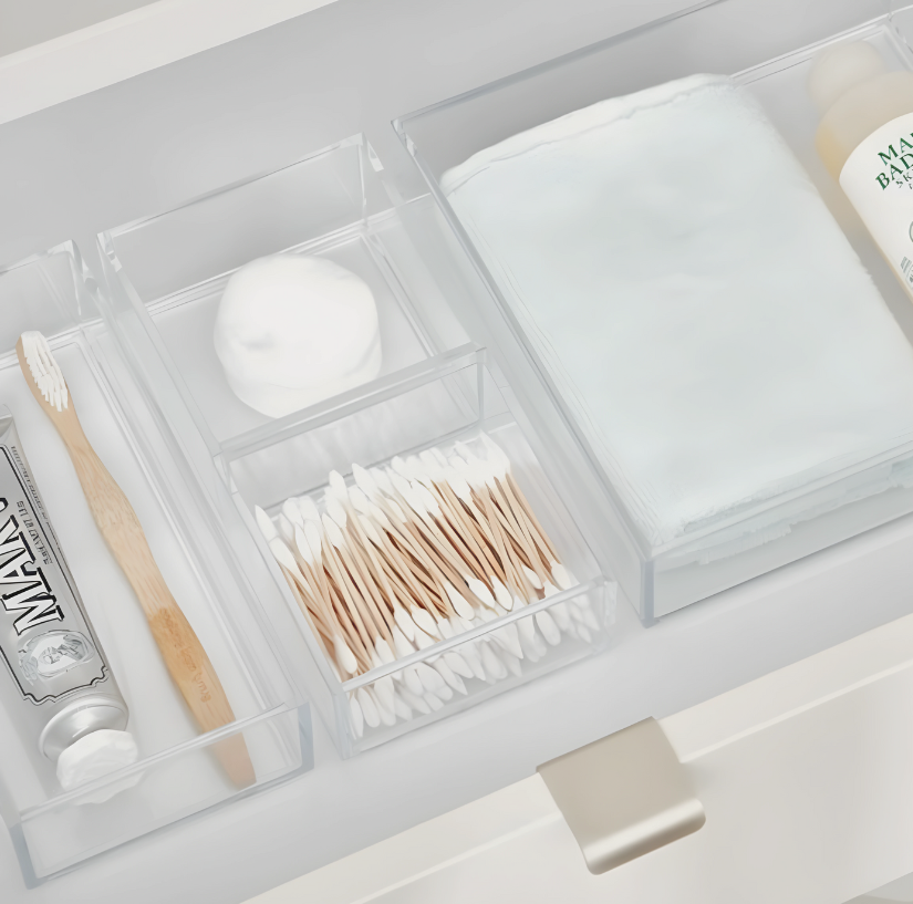 Zahnbürste und Zahncreme in transparentem Fach neben Wattestäbchen und Handtüchern in Schublade.