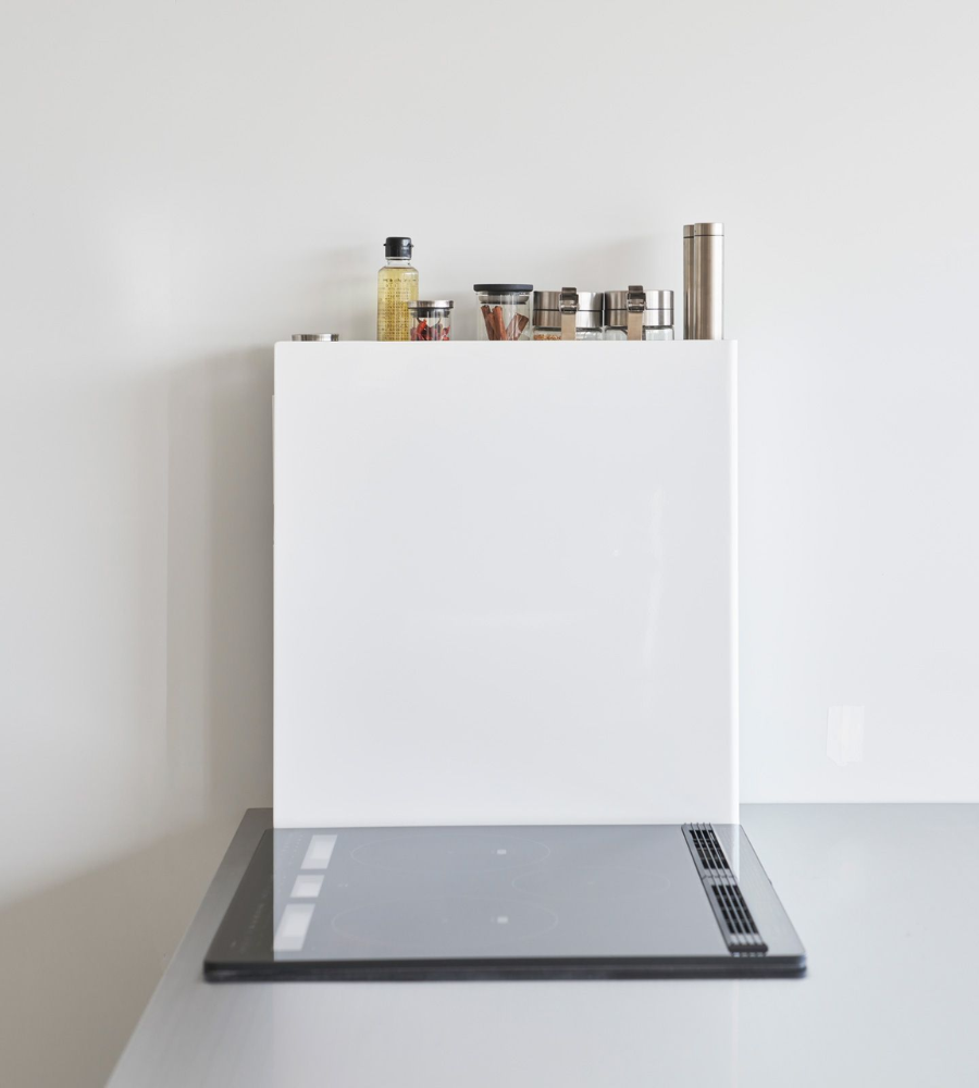 Eine moderne, minimalistische Küche mit weißer Aufkantung, elektrischer Herdplatte und ordentlich angeordneten Gewürzdosen auf dem YAMAZAKI TOWER Gewürzregal 2-stöckig - Weiss über dem Herd.