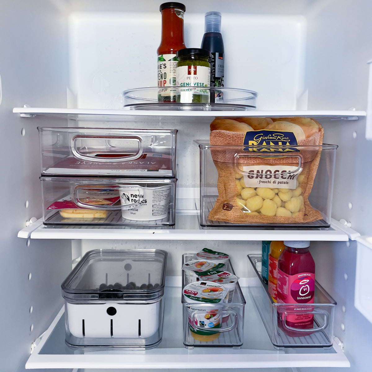 Kühlschrank mit geordneten Lebensmitteln in Plastikbehältern: Saucen oben, Gnocchi mittig, Joghurt unten.