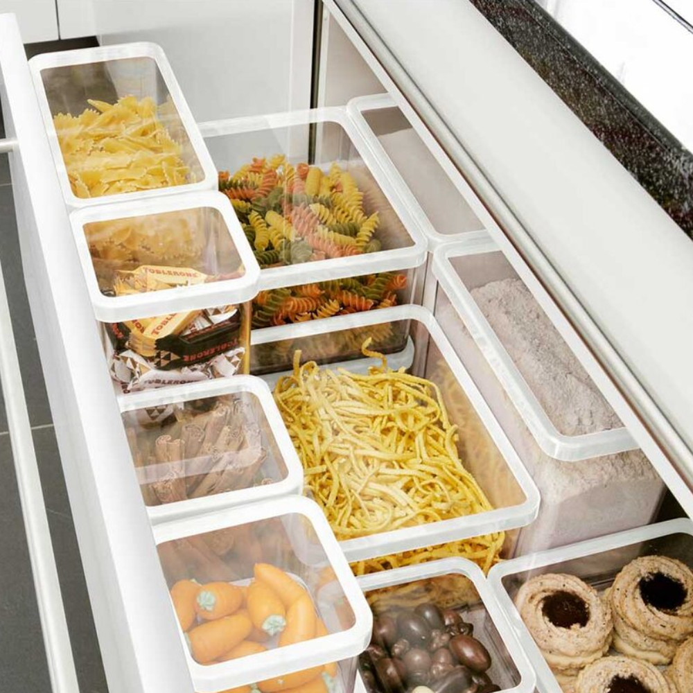 Küchenschublade mit Vorratsdosen für Pasta und Süßigkeiten, weiße Rahmen, dunkle Arbeitsplatte, Text „TORRONI“.