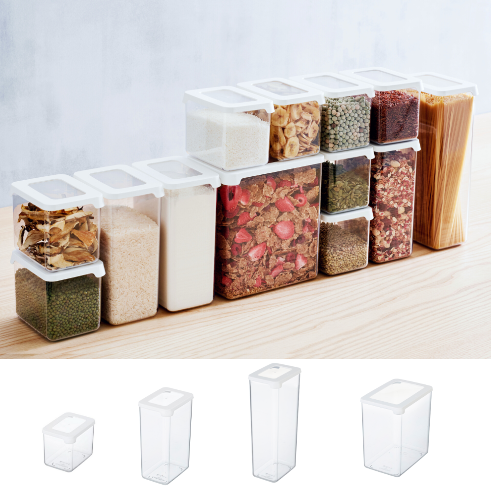 A row of Orthex SmartStore clear-and-white storage containers, filled with pasta, grains, and spices, sits on a light-colored wooden surface. Four empty, stackable containers are displayed below them.