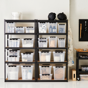 Zwei schwarze Metallregale halten Orthex SmartStore Box KLAR 40x30x18cm (14L) Behälter gefüllt mit Haushalts- und Handwerksartikeln, neben einer Wand mit einer hängenden Schürze und Werkzeugen. Ein kleiner Rollwagen steht daneben.