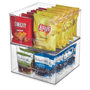 Der iDesign HOME EDIT - Aufbewahrungsbehälter KLAR - OpenFront bewahrt Cheez-It Cracker, Lay's Classic Chips, Cashew-Snack-Mix und schokoladenüberzogene Blaubeeren in zwei übereinanderliegenden Fächern auf.