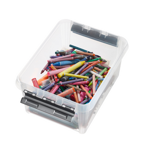 Bunte Wachsmalstifte unsortiert in transparenter Plastikbox auf weißer Fläche.
