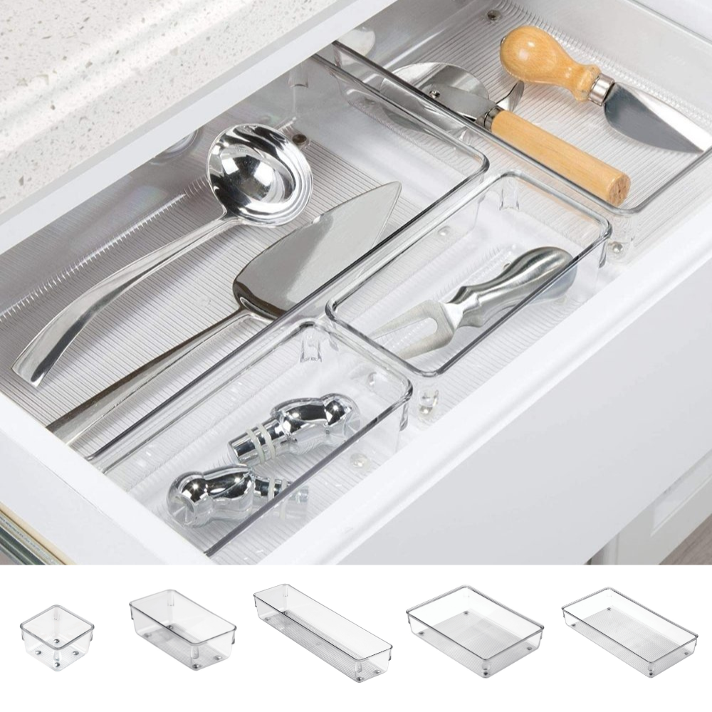 Utensili da cucina in scomparti trasparenti di un cassetto, accanto a scatole trasparenti vuote.